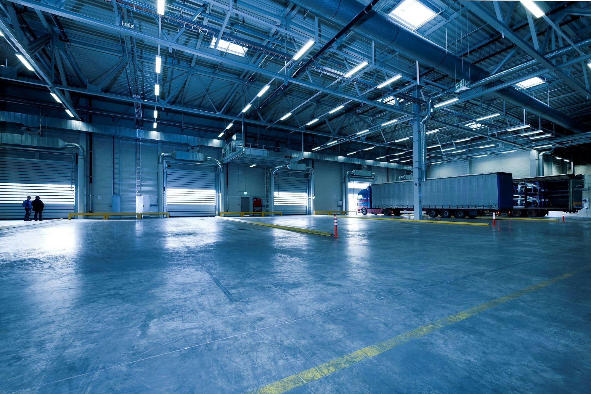 Image of an empty warehouse with lights on but no furniture.