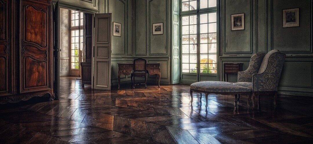 The opulent living room of a Georgian townhouse with large windows and the sun streaming in across the floor.