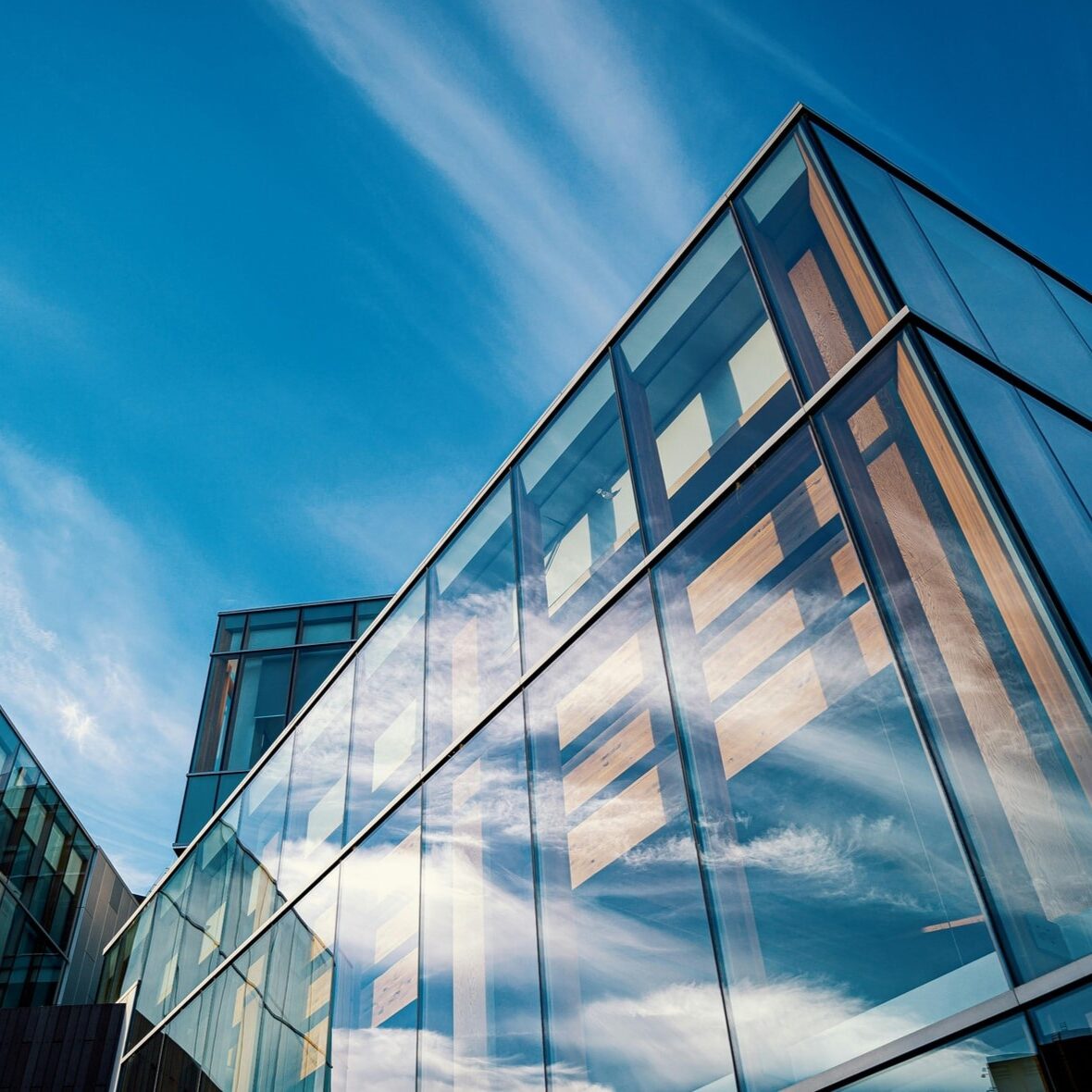 Large glass commercial building with sunny blue skies surrounding it.