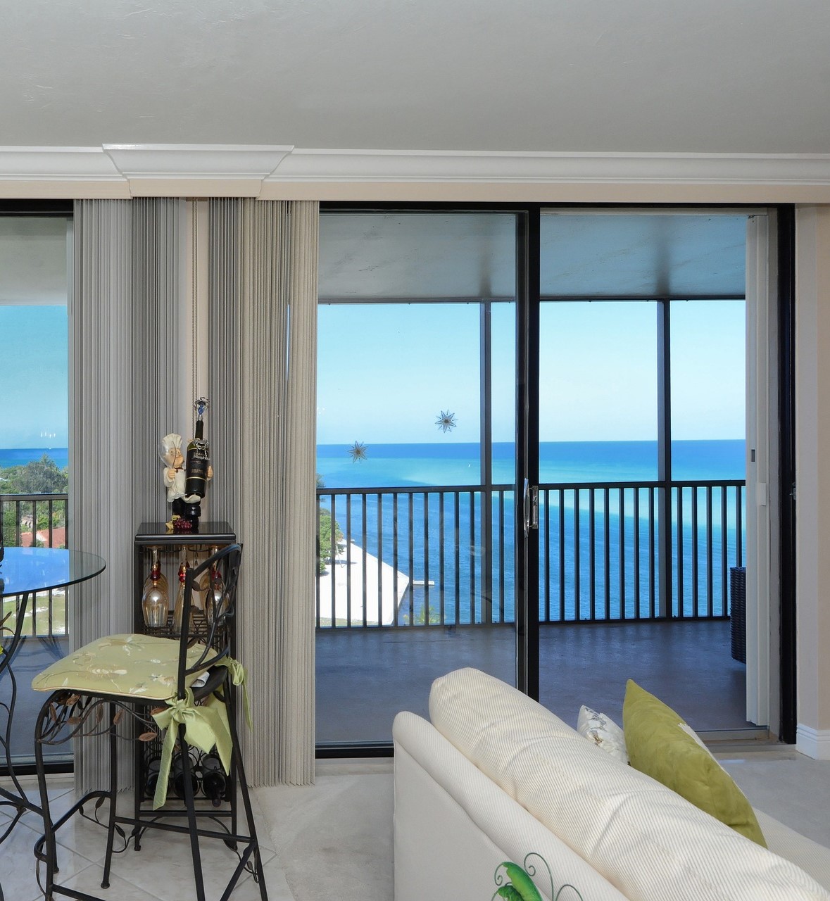 Stunning white penthouse, with a view looking out of balcony doors overlooking bright blue sea.