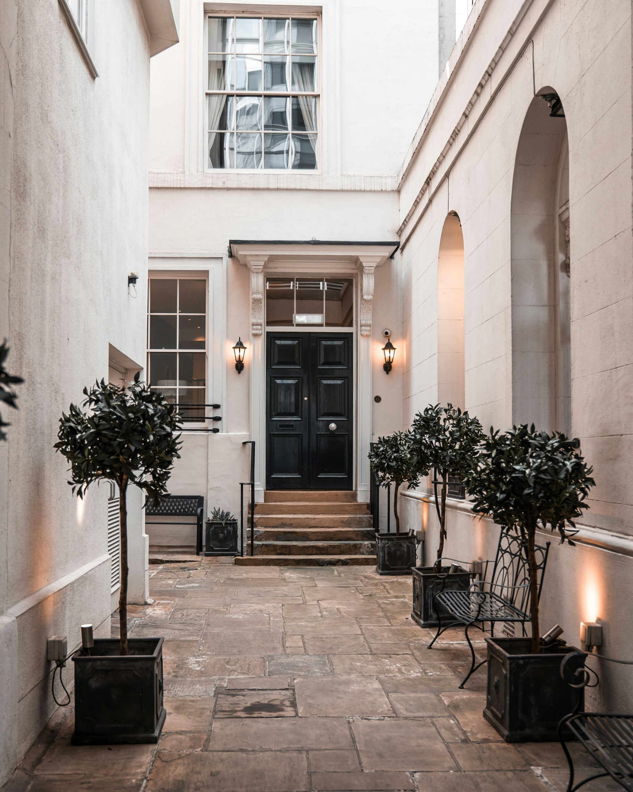 London mews house, black front door with trees either side.