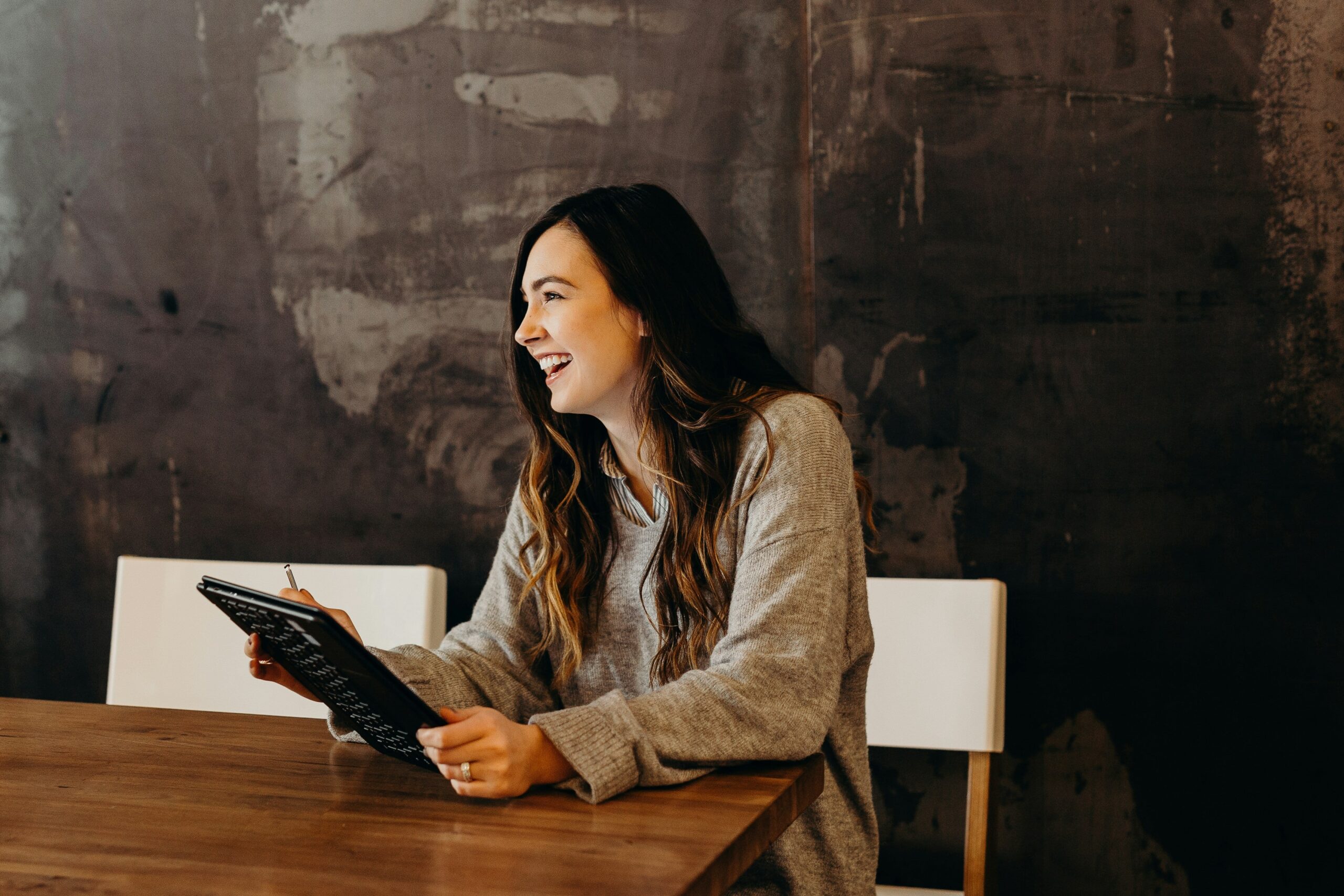 Young professional female, sitting with an iPad and laughing
