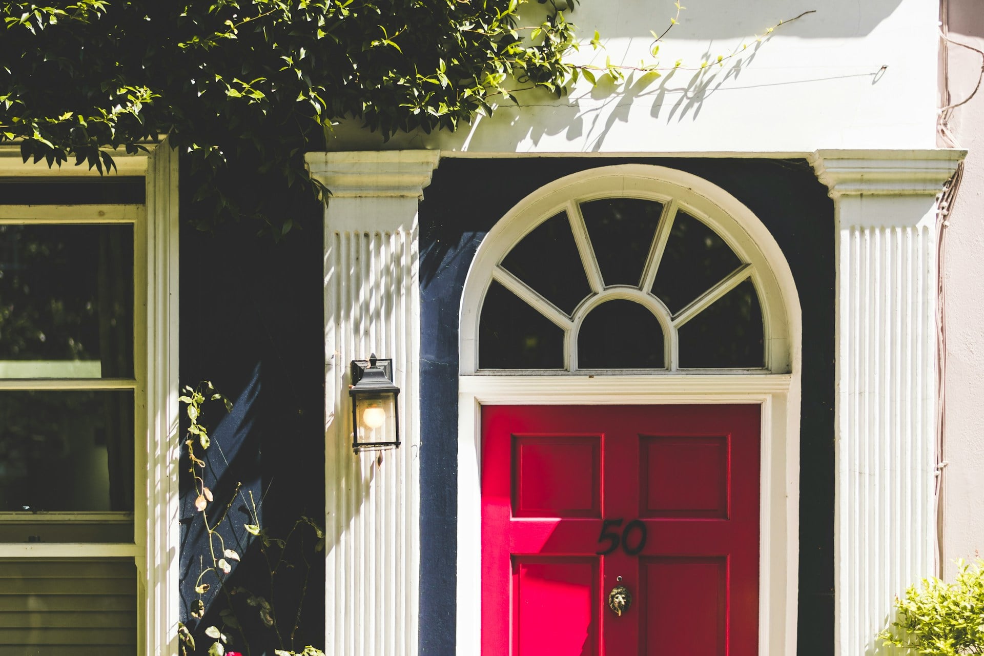 The front of a navy blue house with a bright fuscia pink door