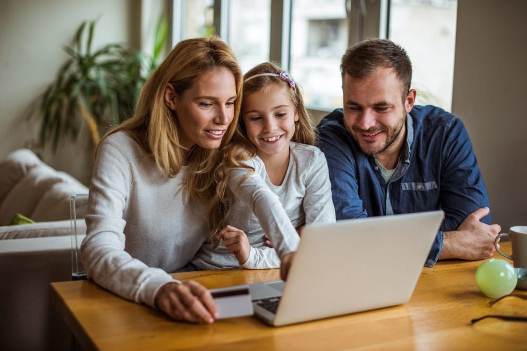Happy family of 3, crowding a laptop
