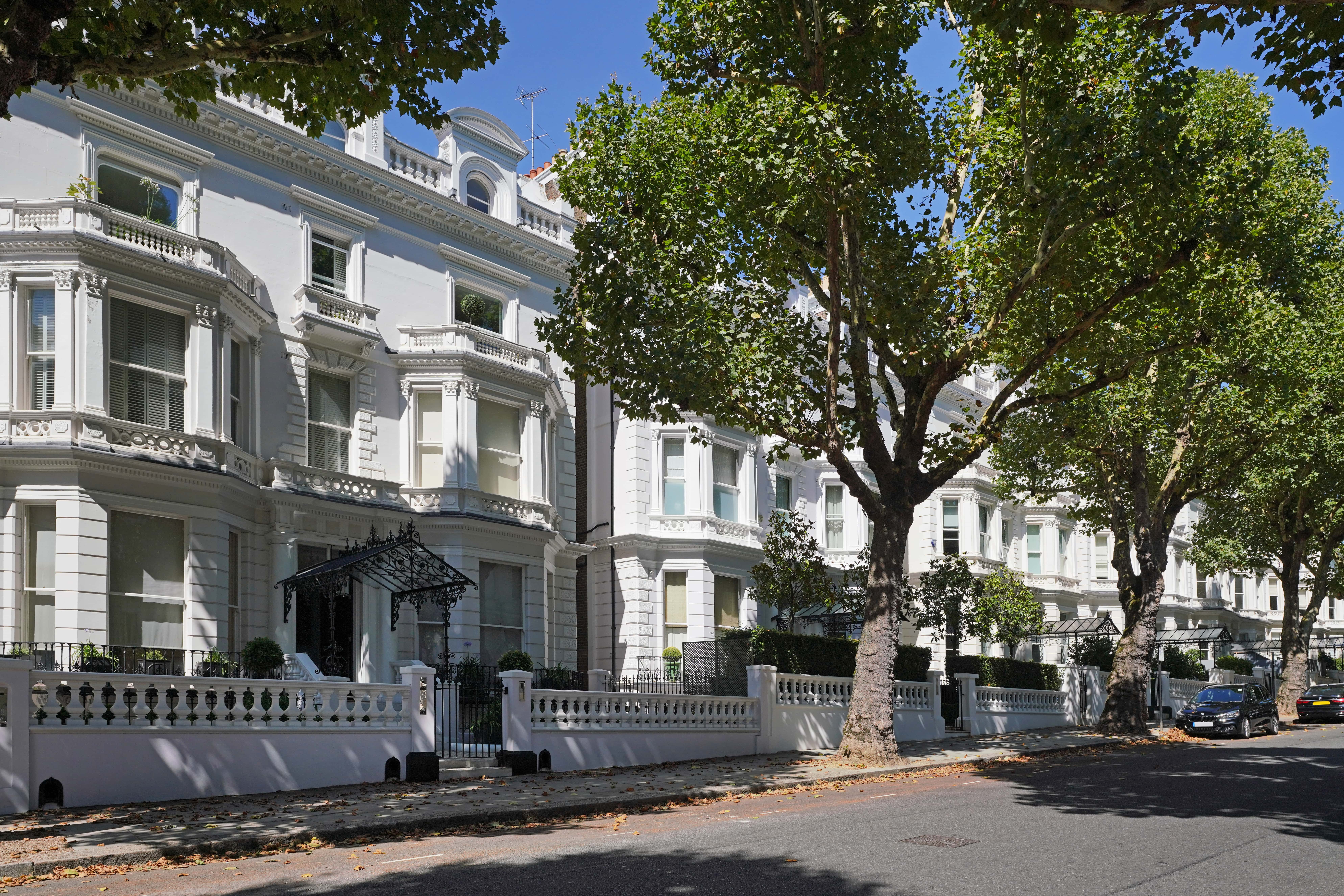 White Georgian townhouses in London surrounded by green trees and blue sky